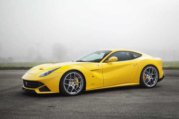 Ferrari F12 amarillo en niebla sobre asfalto