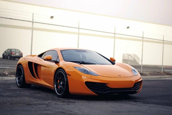 An orange-colored car at the fence