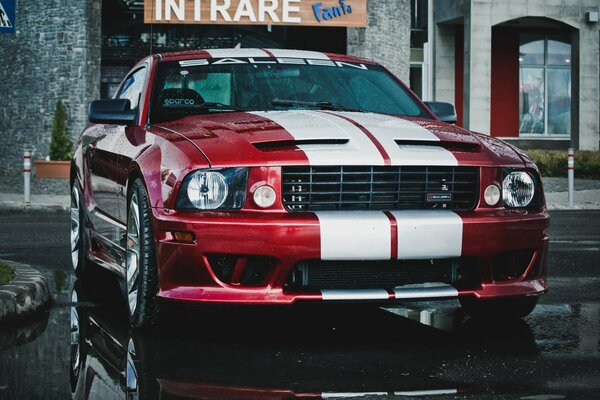 Ford Mustang rojo y blanco bajo la lluvia