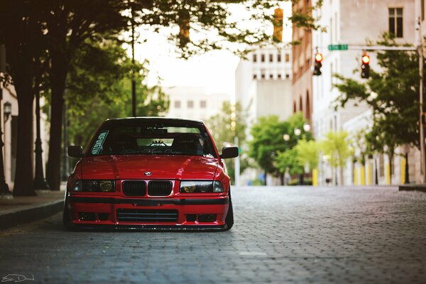 BMW E36 rouge sur pavé gris