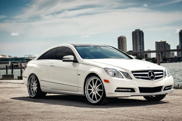 White Mercedes benz e-class coupe on the background of skyscrapers