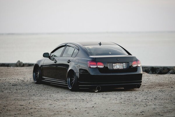 Lexus black car in solitary on a sandy road