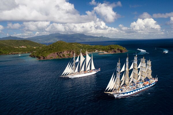 Two sailboats sail past the islands