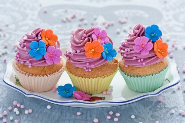 Bright cupcakes are decorated with flowers and multicolored cream