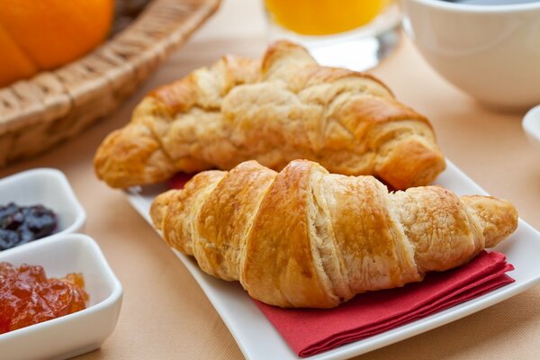 Coppia croissant su un tovagliolo con piattini di marmellata in piedi accanto