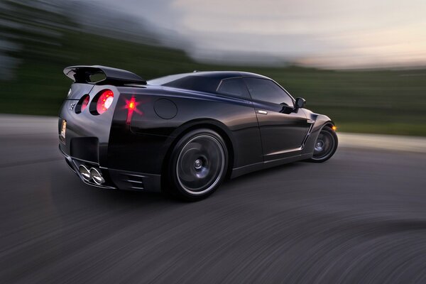 Black Nissan at the entrance to the turn with a blurred background