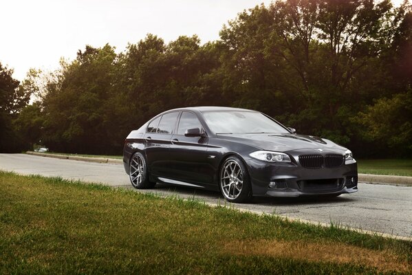 A beautiful, black car is driving along the road