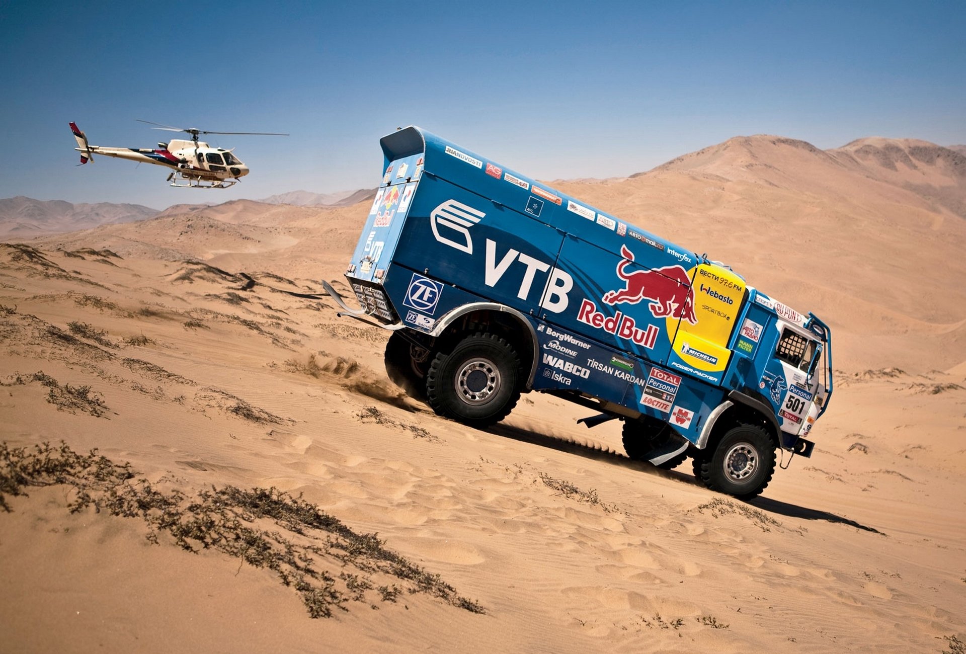 kamaz dakar rallye bleu taureau rouge hélicoptère vue latérale descente voiture auto sable dune