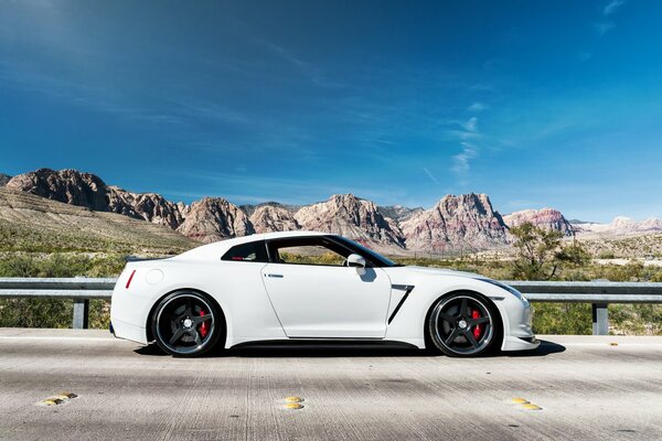 El Nissan blanco se encuentra en el asfalto contra el fondo de las montañas