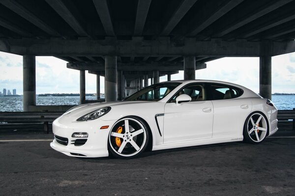 Blanc tuning Porsche Panamera avec de beaux disques, photo sous le pont