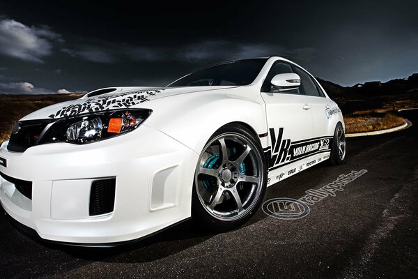 Tuned white subaru with alloy wheels