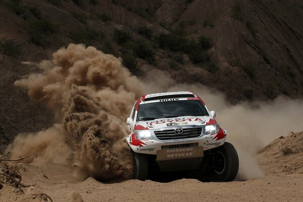 El SUV de Toyota entra espectacularmente en una curva, dejando atrás nubes de polvo