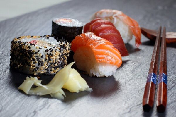 There is an assortment of sushi with chopsticks on the table