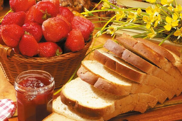 Pan con mermelada y cesta de fresas en decoración de flores