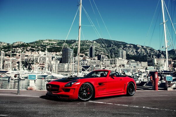 Mercedes rojo en el fondo de edificios y yates