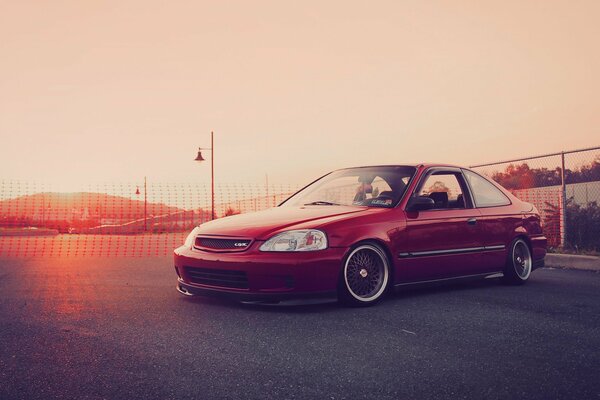 Voiture Honda Civic rouge sur fond de coucher de soleil