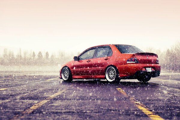 Orange Mitsubishi lancer Evolution hiver. Il neige