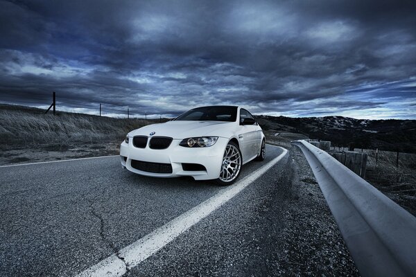 Auto di colore bianco bmw su sfondo di nuvole e strade