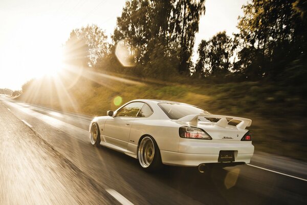 Nissan blanco corriendo al encuentro del sol