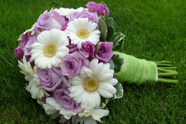 Ein Blumenstrauß mit Kamille und Rosen liegt auf dem Rasen