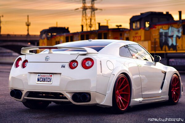 Coche Nissan blanco con ruedas rojas