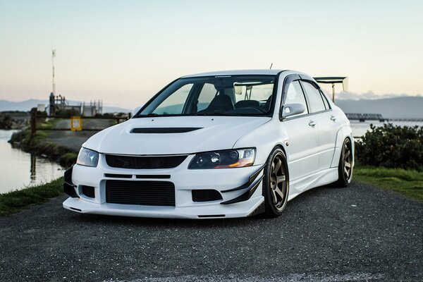 White mitsubishi lancer evo ix near the lake