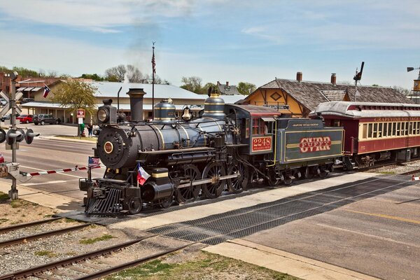 A steam locomotive passes through a railway station