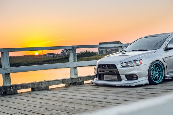 Grauer Mitsubishi auf der Brücke mit Blick auf den Sonnenuntergang