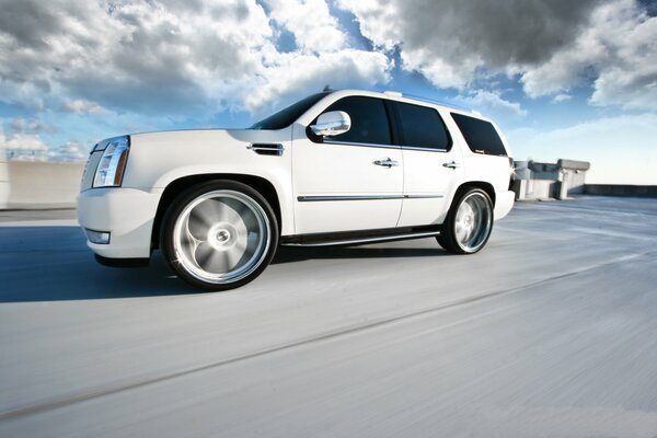 La cadillac escalade blanche Monte rapidement ses enjoliveurs flous sur ses roues