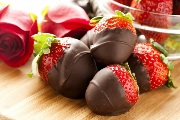 Fresas cubiertas de chocolate y rosas en la mesa