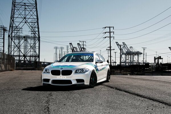 Coche blanco con una franja azul debajo de las líneas eléctricas