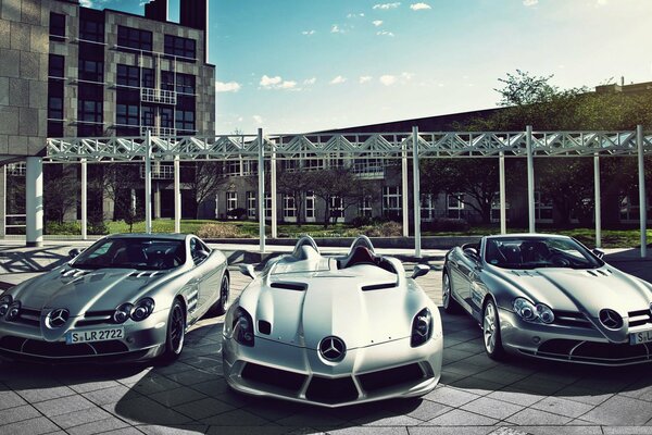 Three sports cars pose at an interesting structure