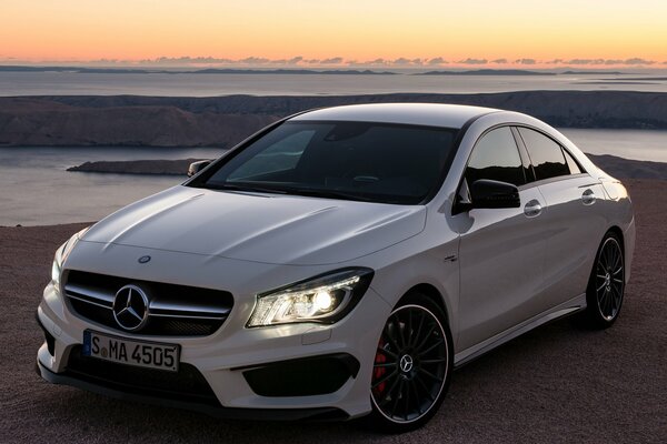 White Mercedes in nature with the headlights on