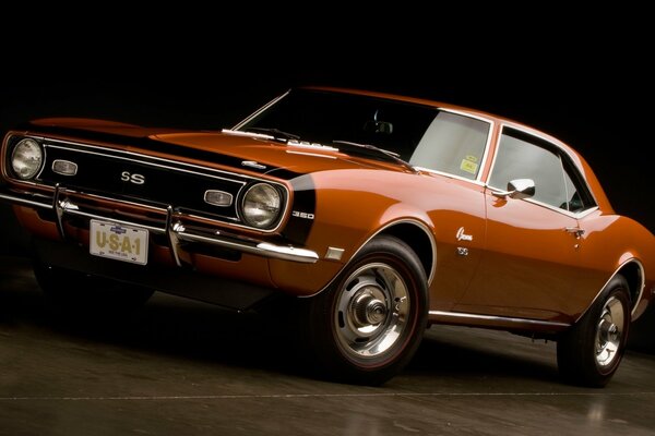 Un Chevrolet Camaro naranja de 1968 sobre un fondo oscuro