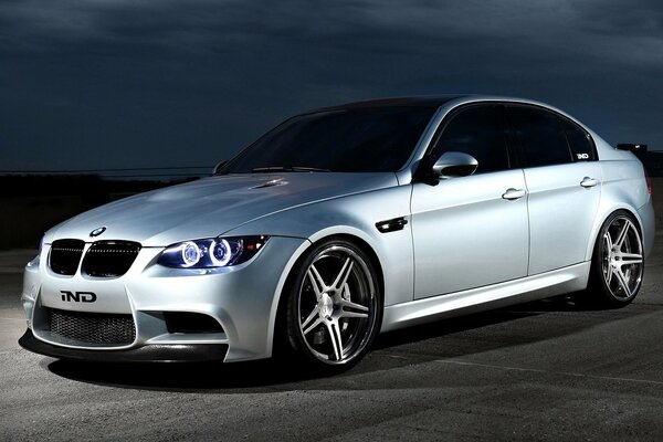 A silver bmw car stands on the asphalt at dusk