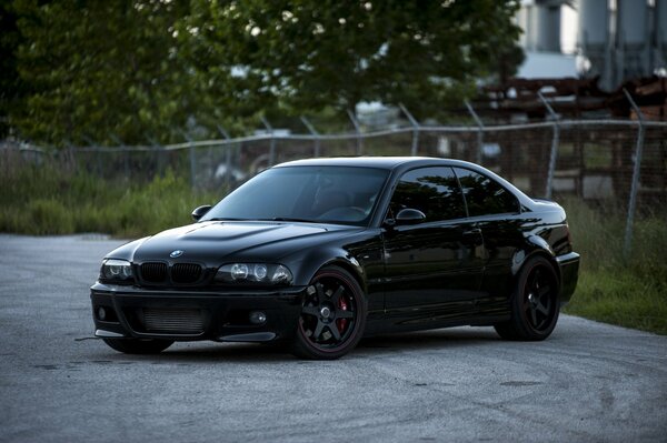 Bmw is black and there is a mesh fence at the back