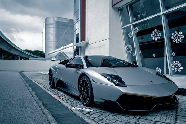 Coche Lamborghini de color gris en la acera