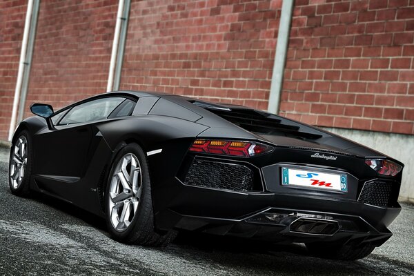 Lamborghini matte black against a brick wall