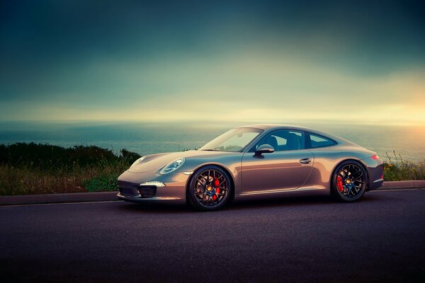 Lilac Porsche sports car on the road against the background of the sea