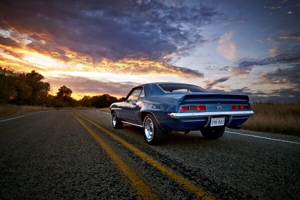 El coche conduce por el camino hacia la puesta del sol