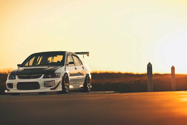 Mitsubishi white car on sunset background