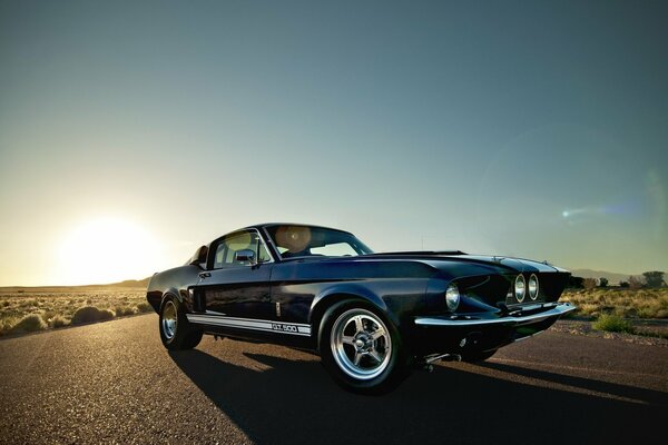 Voiture Ford Mustang sur la route ensoleillée dans le désert