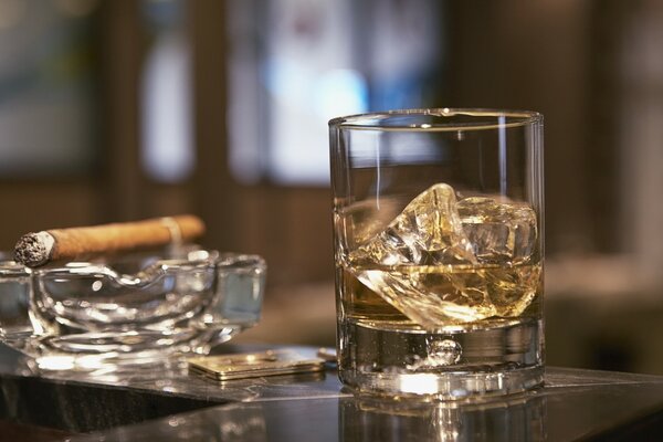 Whisky avec glace et cigare dans un cendrier en verre