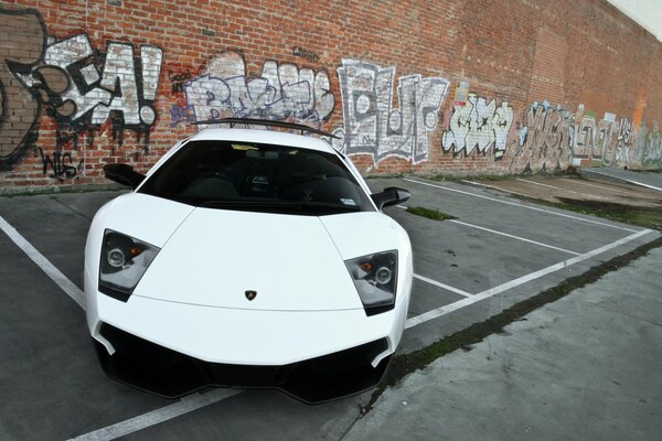 Vorderansicht eines weißen Lamborghini mit trapezförmigen Scheinwerfern auf dem Parkplatz