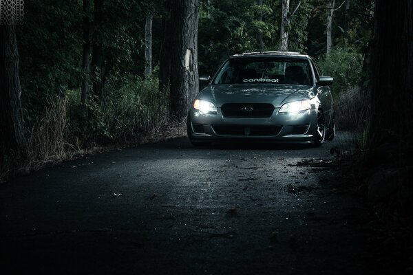 Subaru rides at night with its headlights on on a forest road