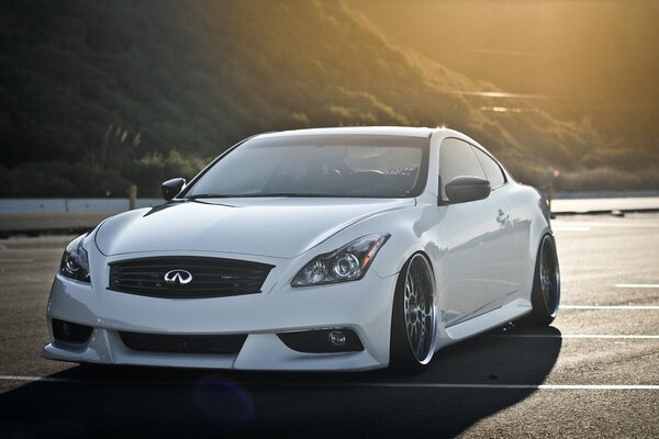 Infiniti blanco en la carretera, detrás de la montaña