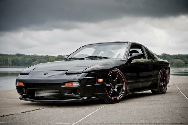 Sports Nissan 240sx on the road against a cloudy sky