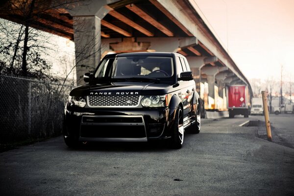 Powerful black range rover on the background of the Vysky bridge