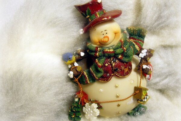 A toy Christmas snowman with a scarf in a hat on a fur background