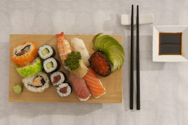 Sushi und Brötchen auf einem Tablett mit Stäbchen und Soße